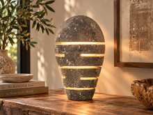 Charger l'image dans la galerie, Lampe en pierre allumée, lumière filtrant par les rainures horizontales