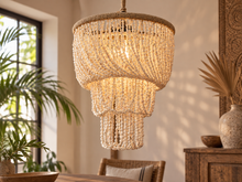 Charger l'image dans la galerie, Lustre en coquillages naturels allumé, suspendu au-dessus d'une table de salle à manger